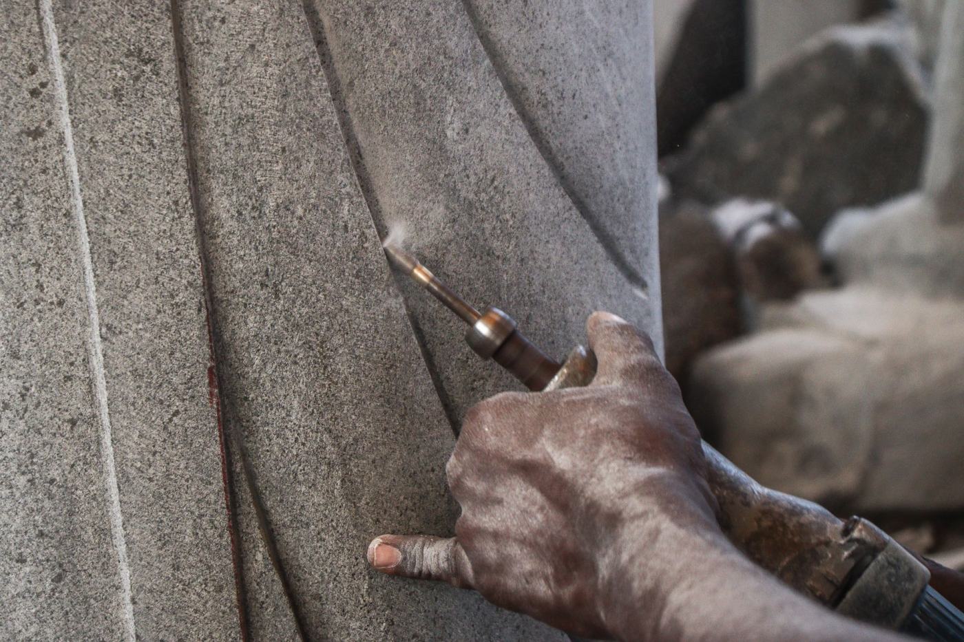 Craftsman's hand hand-finishing a carved stone edge