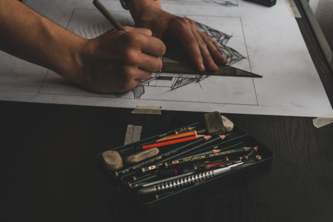 Hand drafting a monument design with pencils and drawing tools